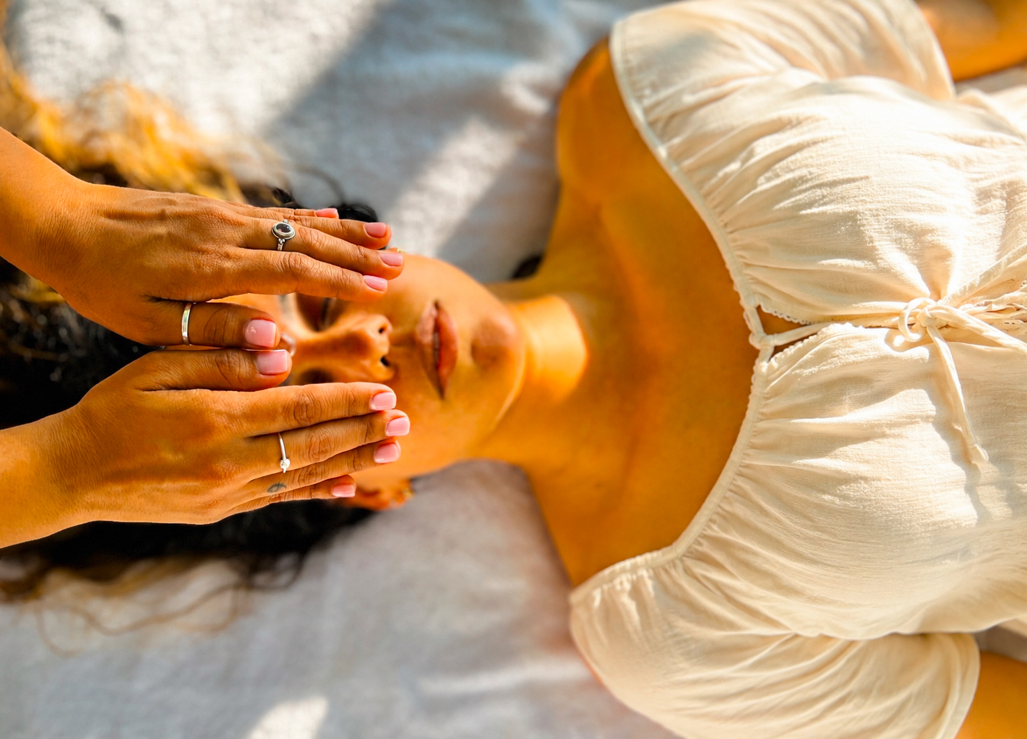 Hands offering Reiki over a resting client’s eyes
